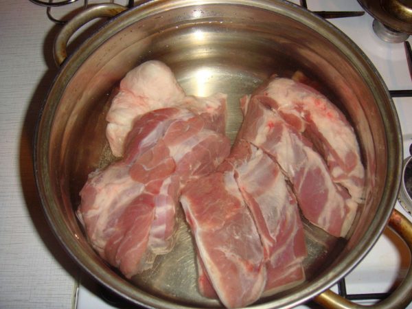 Свиные ребрышки разрежьте на порции и положите в кастрюлю. Залейте водой.