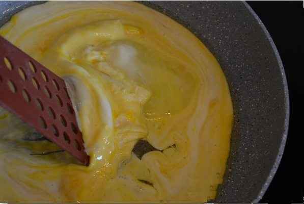 Через четыре-пять секунд, как только "схватится" низ, аккуратно лопаточкой сдвигаем яичницу от краев к центру и краям сковородки, чтобы жидкая составляющая заполнила освободившееся пространство. 