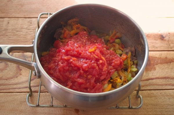 Выкладываем к мясу овощи. Добавляем томатную пасту, сок из банки с фасолью, солим, перчим. Перемешиваем. Закрываем крышкой и тушим 30 минут на минимальном огне.
