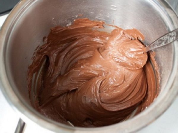 Соединяем в миске сметану, какао-порошок, пудру, размягченное масло. Взбиваем миксером две-три минуты. Добавляем сливки и взбиваем 3 мин.