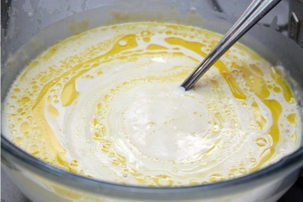 Затем медленно, по краю миски, вмешивайте в тесто топленое масло до полной однородности.