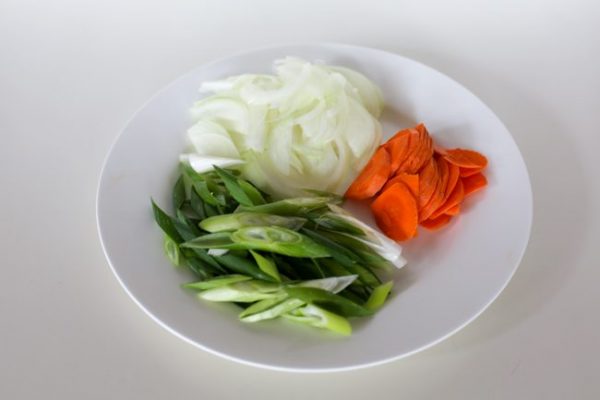 Приготовьте овощи. Тонко нарежьте лук, морковь, зеленый лук и перец.