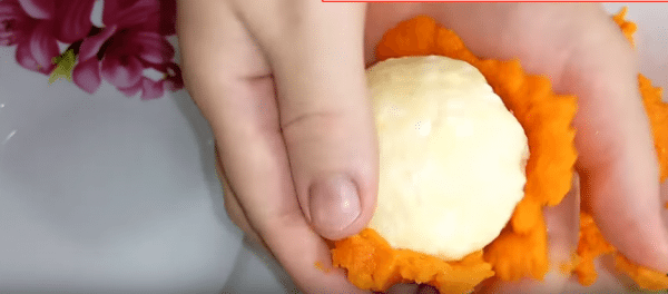 Выкладываем на ладонь натертую морковь, в центр - сырный шарик.