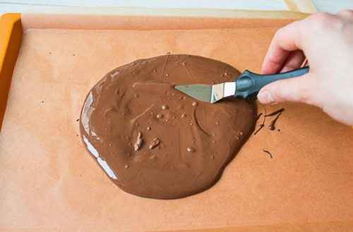 Противень выстилаем силиконовым пергаментом и выливаем на него шоколад. Ровняем шпателем, чтобы получился тонкий пласт. Отправляем в морозилку на 20 минут.